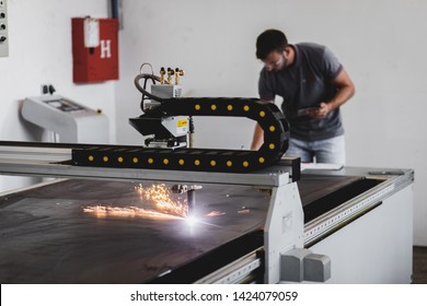 Young engineer setup plasma cutter for work in metalwork workshop.
