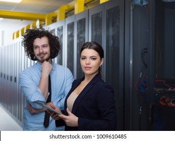 Young IT engineer showing working data center server room to female chief engineer who holding tablet computer