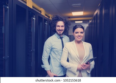 Young IT engineer showing working data center server room to female chief engineer who holding tablet computer
