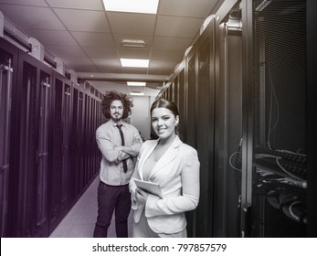 Young IT engineer showing working data center server room to female chief engineer who holding tablet computer