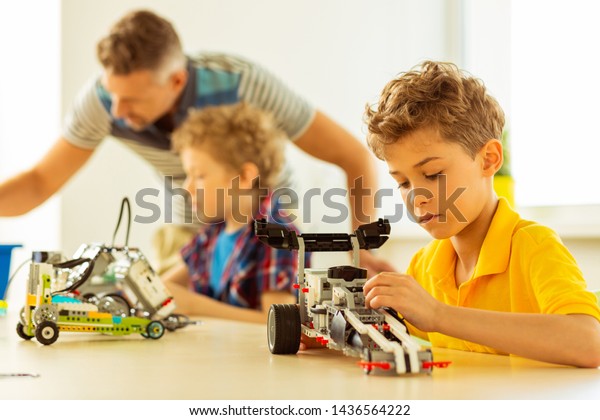 Young engineer. Smart\
blonde boy thinking about his car model while wanting to become an\
engineer