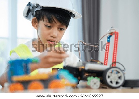 Young Engineer at Work: A focused young boy, wearing a safety hard hat, meticulously assembles a robotic from colorful building blocks, showcasing his passion for STEM education and engineering.