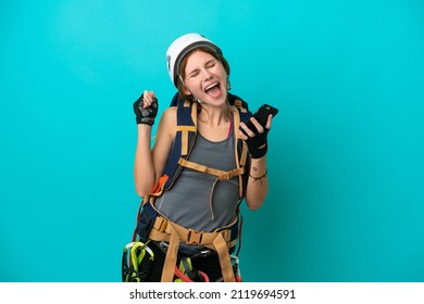 Young English Rock Climber Woman Isolated On Blue Background With Phone In Victory Position