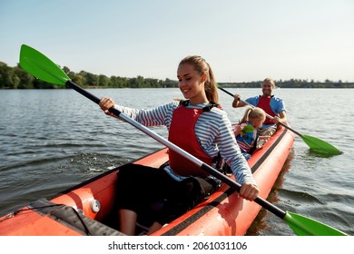 Young enjoying caucasian family floating on kayak with paddles. Concept of rest, leisure and weekend at nature. Extreme water sport. Mother, father and daughter wearing life vests. Summer sunny day