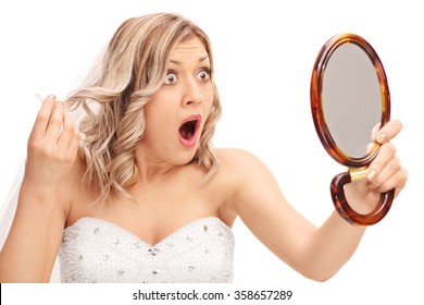 Young enraged bride looking at her hairstyle in a mirror isolated on white background