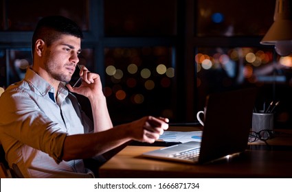 Young Entrepreneur Guy Talking On Phone With Client Negotiating Business Deal Working Overnight In Modern Office. Copy Space - Shutterstock ID 1666871734
