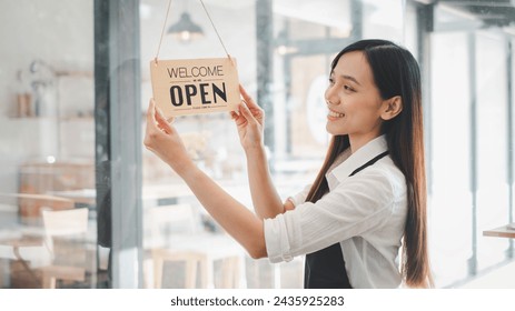 Young entrepreneur holding open sign on glass door at cafe - Powered by Shutterstock