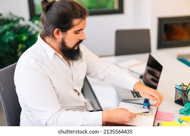 Young entrepreneur stapling papers while working at home. 