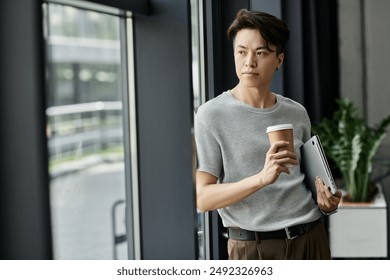 A young entrepreneur takes a moment to contemplate the future while holding a coffee and laptop. - Powered by Shutterstock