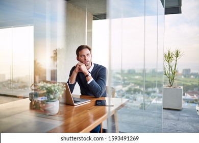 Young Entrepreneur Thinking Up New Ideas While Working On A Laptop At A Table At Home