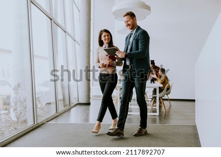 Young entrepreneurs walking together and using digital tablet in the modern office