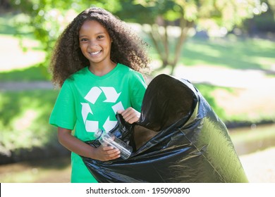 Young environmental activist smiling at the camera picking up trash on a sunny day