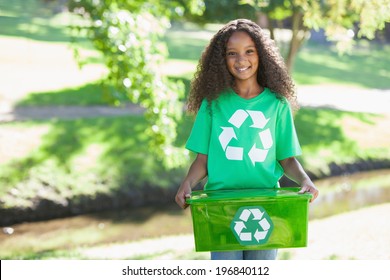 Young environmental activist smiling at the camera holding box on a sunny day - Powered by Shutterstock