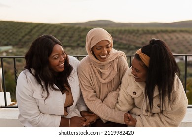 Young Ethnic Friends Laughing Together Outdoors. Group Of Multicultural Female Friends Having A Good Time While Leaning On A Bridge. Diverse Young Women Hanging Out Together On The Weekend.