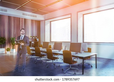 Junge europäische Geschäftsleute mit Notebook, das im Büro im Freien steht, mit weißen und hölzernen Wänden und langen Computertischen. Tonbild