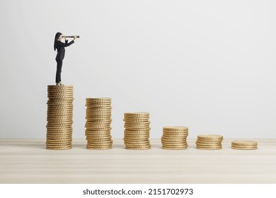 Young european businesswoman with binoculars standing on stacked golden coins chart on white background with mock up place. Finance, stock and earnings concept