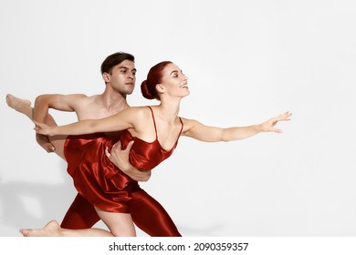 Young European Dance Couple Dancing Classical Ballet Dance. Choreography Concept. Man Holding Smiling Woman In Hands. Woman Wearing Red Nightie. Beautiful People Isolated On White Background In Studio