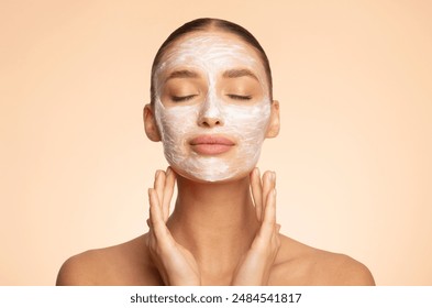 Young European lady posing with facial mask and closed eyes, enjoying beauty skincare treatments, standing over beige background - Powered by Shutterstock