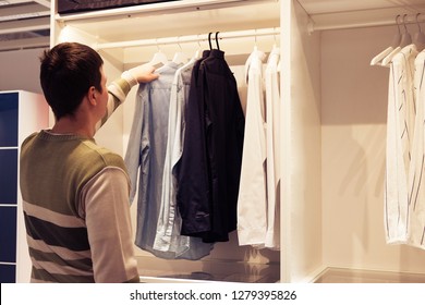 Young European Man With Dark Hair Brings Wardrobe Order Puts Everything In Its Place Hides Things In Boxes. Closet Organized.