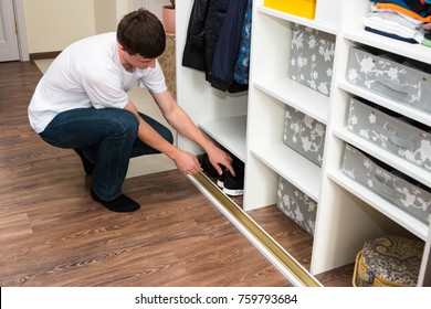 Young European Man With Dark Hair Brings Wardrobe Order Puts Everything In Its Place Hides Things In Boxes. Closet Organized.