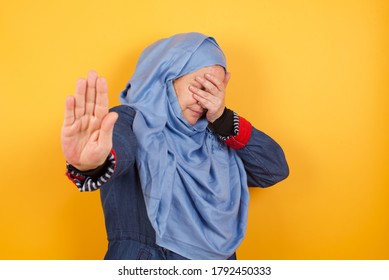 Young European Muslim Woman Covers Eyes With Palm And Doing Stop Gesture, Tries To Hide From Everybody. Don't Look At Me, I Don't Want To See, Feels Ashamed Or Scared.