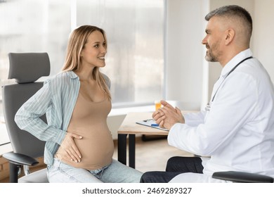 Young European pregnant woman visiting her male gynecologist doctor in clinic, lady sitting on chair and talking to her doc - Powered by Shutterstock