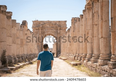Young European tourist visiting the ruins of the city of Jerash, Jordan. Middle aged male on the walk of the destroyed Roman columns in the historic ancient city.