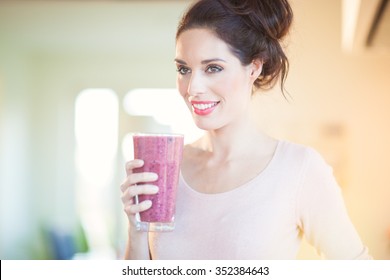 Young European Woman Drinking Fresh Berry Smoothie In Kitchen. Healthy Eating Concept. Full Glass Of Healthy Juice.