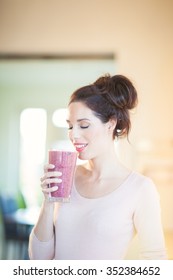 Young European Woman Drinking Fresh Berry Smoothie In Kitchen. Healthy Eating Concept. Full Glass Of Healthy Juice.