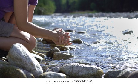 Young European woman hiker washing hands by the river

