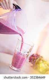 Young European Woman Making Fresh Berry Smoothie In Kitchen. Healthy Eating Concept. Full Glass Of Healthy Juice.