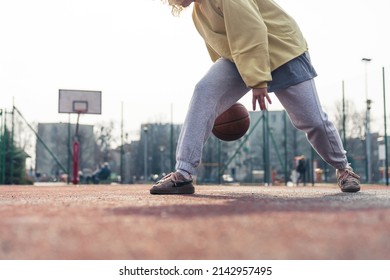 Young European Woman Plays Basketball On The Sports Field, Bouncing The Ball, No Face Visible Copy Space . High Quality Photo