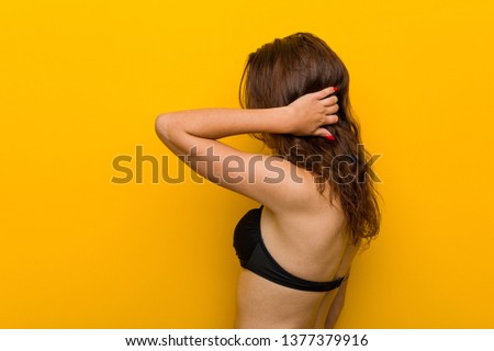 Young european woman wearing bikini from behind thinking about something.