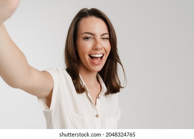 Young european woman winking while taking selfie photo isolated over white background - Shutterstock ID 2048324765