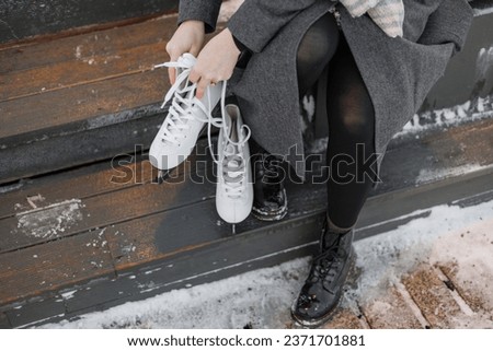 young European woman in winter clothes is skating, lady with red hair is wearing white skates on a snow rink in park. happy millennial woman is having fun. winter christmas holidays