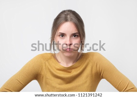 Young european woman in yellow sweater looking with offended look, being dissatisfied with something. Wife is angry with her husband