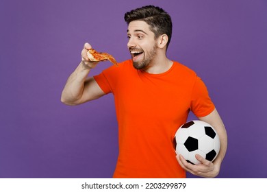 Young Excited Amazed Fan Man Wears Orange T-shirt Cheer Up Support Football Sport Team Hold In Hand Soccer Ball Eat Slice Of Italian Pizza Watch Tv Live Stream 2024 Isolated On Plain Purple Background