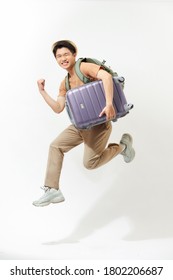 Young Excited Asian Tourist Man With Baggage Jumping In Mid-air Ready To Travel Isolated