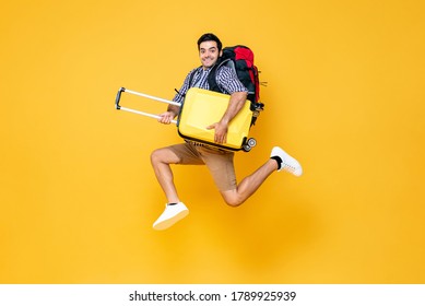 Young excited Caucasian male tourist with baggage jumping in mid-air ready to travel isolated on colorful studio yellow background