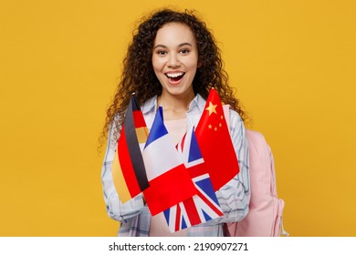 Young Excited Cheerful Happy Black Teen Girl Student She Wear Casual Clothes Backpack Bag Hold Many Different Flags Isolated On Plain Yellow Color Background. High School University College Concept