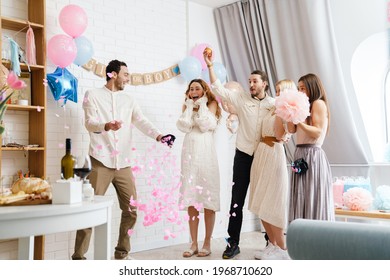 Young excited couple blowing up surprise balloon during gender reveal party indoors - Shutterstock ID 1968710620