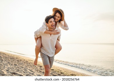 Young excited couple two friends family man woman in casual clothes boyfriend give piggyback ride to joyful girlfriend sit on back at sunrise over sea beach ocean outdoor seaside in summer day evening - Powered by Shutterstock