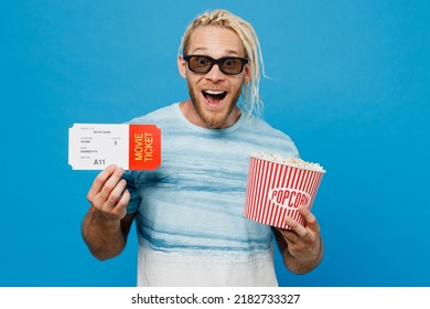 Young Excited Exultant Jubilant Surprised Shocked Happy Cool Man In 3d Glasses Watch Movie Film Hold Bucket Of Popcorn In Cinema Ticket Isolated On Plain Pastel Light Blue Background Studio Portrait