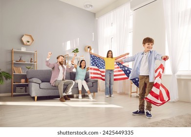 Young excited happy American parents with two children boy and girl sitting at home with flag of united states celebrating Independence Day. Family patriotism and US patriotic holiday concept. - Powered by Shutterstock