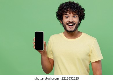 Young excited happy Indian man 20s in basic yellow t-shirt hold in hand use mobile cell phone with blank screen workspace area isolated on plain pastel light green background People lifestyle concept - Powered by Shutterstock