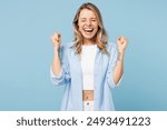 Young excited happy woman she wears white top shirt casual clothes doing winner gesture celebrate clenching fists isolated on plain pastel light blue cyan background studio portrait. Lifestyle concept