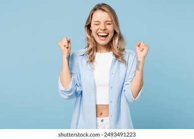 Young excited happy woman she wears white top shirt casual clothes doing winner gesture celebrate clenching fists isolated on plain pastel light blue cyan background studio portrait. Lifestyle concept - Powered by Shutterstock