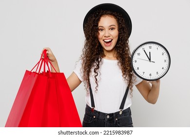 Young Excited Happy Woman Wear T-shirt Hat Hold In Hand Red Paper Package Bags After Shopping Show Clock Time Isolated On Plain Solid White Color Background Studio. Black Friday Sale Buy Day Concept