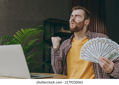 Young excited man he wear shirt work study on laptop pc computer hold cash money sit alone at table in coffee shop cafe relax rest in restaurant in free time. Freelance mobile office business concept - Shutterstock ID 2179232061