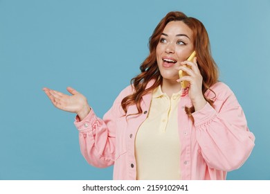 Young Excited Redhead Chubby Overweight Woman 30s With Curly Hair Wear Pink Shirt Casual Clothes Talk By Mobile Cell Phone Isolated On Pastel Blue Background Studio Portrait People Lifestyle Concept